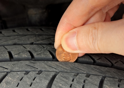 Checking tire tread depth and wear with a penny. If you can see all of Lincoln's head, your tread depth is less than 1/16th of an inch and it's time to replace your tires.